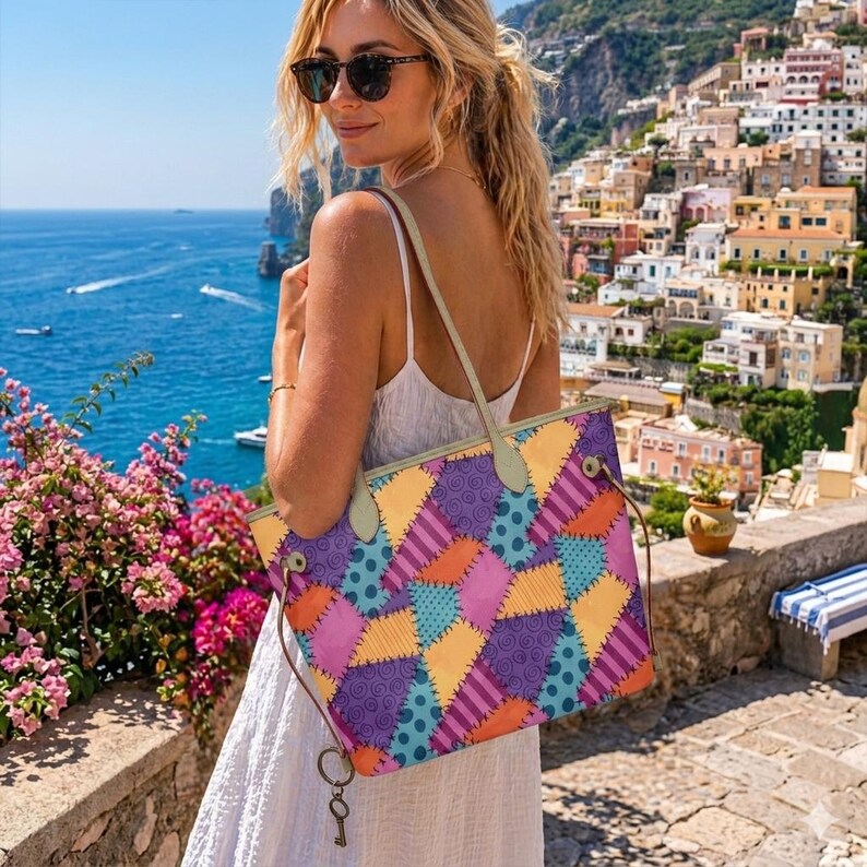 May include: A tote bag featuring a colourful patchwork design with yellow, purple, blue, and orange segments. The pattern includes polka dots, swirls, and stripes with visible stitched detailing. It has light-coloured shoulder straps and a metal key charm.