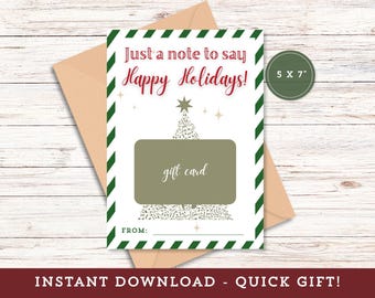 May include: A 5x7 inch holiday gift card with the message "Just a note to say Happy Holidays!" in red script. The card features a Christmas tree design and a space for a gift card. A brown envelope is behind the card.