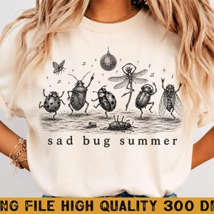 May include: A cream-colored t-shirt featuring a black ink-style graphic of various insects dancing under a disco ball. The insects include a ladybug, a beetle, and a dragonfly. The text "sad bug summer" is printed in a simple black font below the art.