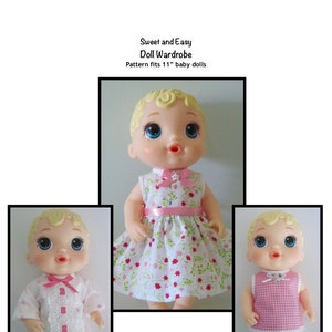 May include: Three 11-inch baby dolls wearing different outfits. The doll on the left is wearing a white dress with pink stars and lace trim. The doll in the middle is wearing a white dress with pink flowers and a pink ribbon. The doll on the right is wearing a pink and white gingham top and white pants.