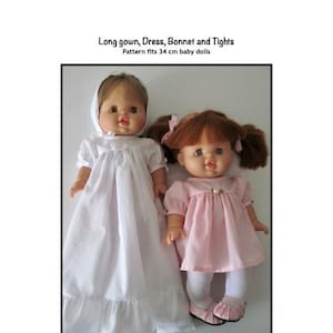 May include: Two baby dolls wearing handmade doll clothes. The doll on the left is wearing a white long gown with lace trim. The doll on the right is wearing a pink dress with white tights and pink shoes. The text on the image reads "Long gown, Dress, Bonnet and Tights. Pattern fits 34 cm baby dolls. Kathy. Anne Designs for dolls."