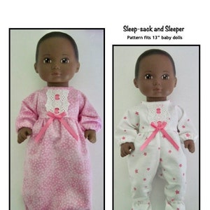 May include: Two 13-inch baby dolls wearing pink and white pajamas with star patterns. The doll on the left is wearing a pink sleep sack with white stars and a pink bow. The doll on the right is wearing a white pajama set with pink stars and a pink bow. The text "Sleep-sack and Sleeper" and "Pattern fits 13" baby dolls" is above the dolls. The text "Kathy Anne Designs for dolls" is below the dolls.