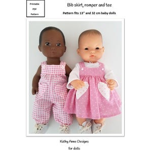 May include: Two baby dolls dressed in handmade outfits. One doll wears a pink gingham romper, and the other wears a pink polka dot bib skirt over a white shirt. The text on the image reads "Bib skirt, romper and tee" and "Pattern fits 13" and 32 cm baby dolls."