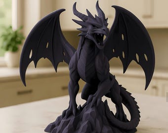 Op de afbeelding: Een donkergrijze drakenfiguur met uitgespreide vleugels en een open mond, geplaatst op een rotsachtige basis. De draak heeft gedetailleerde schubben, hoorns en klauwen. Het beeldje is een decoratief item.