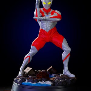 May include: A detailed figurine of a superhero in a dynamic pose. The figure is predominantly red and silver, with yellow eyes and a blue chest emblem. It stands on a base with miniature buildings and water features, set against a dark blue backdrop.