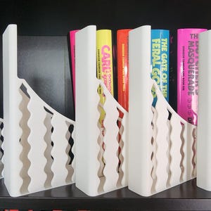 May include: A white ceramic mug with a black handle and the text "But First, Coffee" in a handwritten style. The mug is on a white surface. The mug is approximately 4 inches tall.
