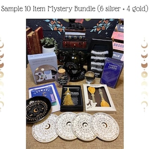 Op de afbeelding: Een verzameling mystieke items, waaronder tarotkaarten, een kristallen bol en decoratieve onderzetters met hemelse ontwerpen. De items zijn gerangschikt op een tafel, met de tekst "Sample 10 Item Mystery Bundle (6 silver + 4 gold)" bovenaan.
