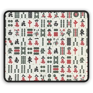 Puede incluir: Una esterilla rectangular para el juego de Mahjong con borde negro. La esterilla está llena de fichas blancas con caracteres y símbolos chinos en rojo, verde y negro. Las fichas están dispuestas en un patrón de cuadrícula.