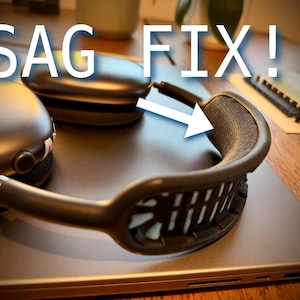 以下が含まれることがあります： 黒いヘッドフォンとグレーのメッシュヘッドバンド。ラップトップの上に置かれています。「SAG FIX！」というテキストがヘッドフォンの上に白で表示され、矢印がヘッドバンドを指しています。