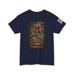 May include: Navy blue t-shirt featuring a graphic with a pirate skull, the text "BUT FAFO MEET THE DEEP", and "OPERATION SOUTHERN SPEAR EST. 2025" over an American flag design. The shirt has a ribbed collar and short sleeves.