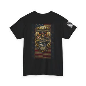 May include: Black t-shirt featuring a graphic design with a skull wearing an eye patch, an American flag background, and the words "EAGLES SHIELDS TRIDENTS" and "FAFO MEET THE DEEP EST. 2023". The shirt also has the word "SEMPER" on the sleeve.
