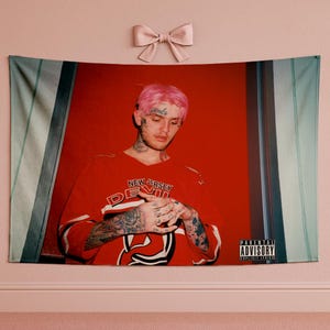 May include: A red tapestry featuring a portrait of a person with pink hair, wearing a red jersey with the text "NEW JERSEY DEVILS". The tapestry has a red background and a Parental Advisory warning.