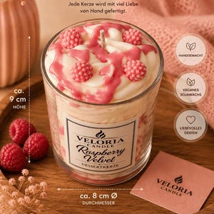 Puede incluir: Una vela en frasco de vidrio con remolinos de cera blanca, detalles de cera en forma de frambuesa y goteos rosas. La etiqueta dice Veloria Candle Raspberry Velvet Dessertkerze. Mide 9 cm de altura y 8 cm de diámetro.