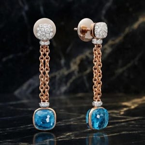 Puede incluir: Un par de pendientes colgantes de oro rosa. Cada pendiente presenta una parte superior redonda con diamantes, una cadena y una gema azul cuadrada en la parte inferior. Los pendientes se muestran sobre un fondo oscuro.