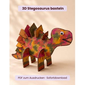 May include: A 3D Stegosaurus dinosaur craft made from cardboard with a multi-colored painted finish, featuring a single googly eye and upright dorsal plates. The text 3D Stegosaurus basteln and PDF zum Ausdrucken · Sofortdownload are visible.