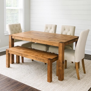May include: A wooden dining table with a matching bench and four upholstered chairs. The table and bench are a warm brown color, and the chairs have beige fabric. The room has a neutral color palette.