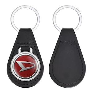 May include: Black leather keychain with a silver ring. The keychain features a red and silver emblem with a white logo. The back of the keychain is plain black leather.