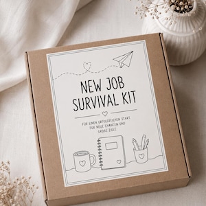 May include: A square brown cardboard box featuring a white label with black line art illustrations of a mug, a notebook, and a pencil holder. The text reads NEW JOB SURVIVAL KIT, FÜR EINEN ERFOLGREICHEN START, FÜR NEUE CHANCEN UND GROBE ZIELE.