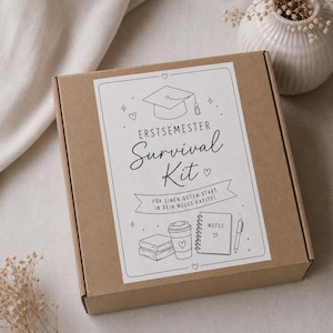Könnte beinhalten: Ein quadratischer brauner Karton mit einem weißen rechteckigen Etikett, das schwarze Strichzeichnungen einer Doktorhut-Kappe, Büchern, einem Kaffeebecher und einem Notizbuch zeigt. Der Text lautet: ERSTSEMESTER Survival Kit, FÜR EINEN GUTEN START IN DEIN NEUES KAPITEL.
