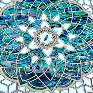 May include: A wooden box with a geometric design inlaid with iridescent abalone shell. The center of the design features a stylized flower with a lightning bolt in the center.