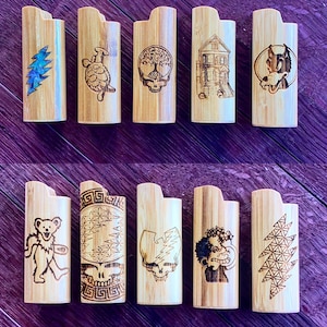 May include: Ten wooden lighter cases with various designs, including a skull, a turtle, a house, a dog, a bear, a flower, a lightning bolt, and a geometric pattern.