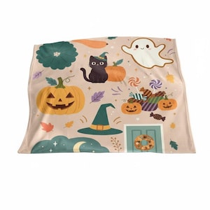 Könnte beinhalten: Eine Halloween-Decke mit verschiedenen Illustrationen. Das Design umfasst einen Kürbis, eine schwarze Katze mit Hexenhut, einen freundlichen Geist und verschiedene Süßigkeiten und Kürbisse. Die Decke hat eine hellbeige Farbe.
