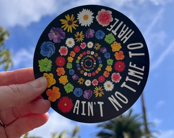 May include: A black and white sticker with a colorful flower design and the text "Ain't No Time To Hate".