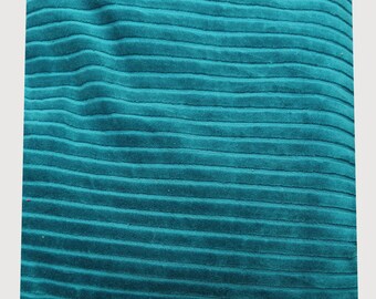 May include: Teal corduroy fabric with a ribbed texture. The fabric has a soft, velvety appearance and is arranged in horizontal lines. The color is a deep, saturated teal, suitable for upholstery or apparel.