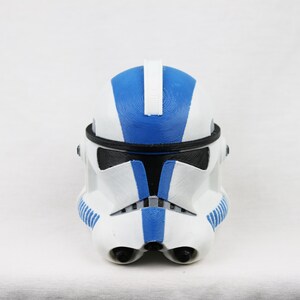 Puede incluir: Un casco de soldado clon de Star Wars blanco y azul con una visera negra.