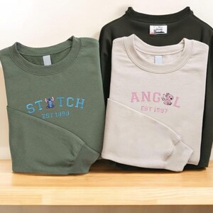 a pair of sweatshirts with the same design, laid out on a wooden surface.