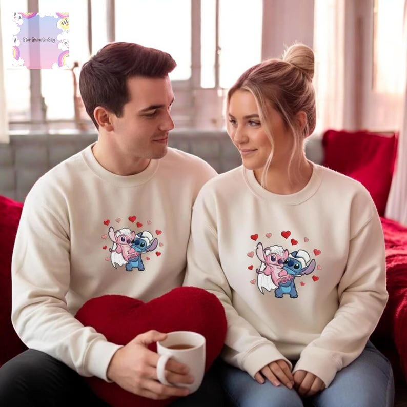 A man and a woman are sitting together on a couch, wearing matching white sweatshirts with a cartoon character design.