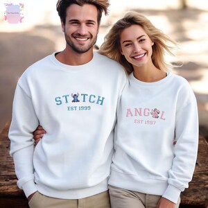 A man and a woman are standing next to each other, both wearing white sweatshirts with the same design.