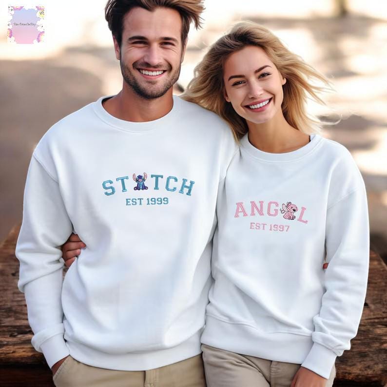 A man and a woman are standing next to each other, both wearing white sweatshirts with the same design.