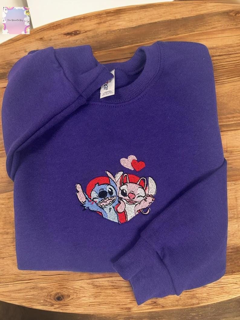 A purple sweatshirt with a cartoon character design on it, featuring two cats and a heart symbol.