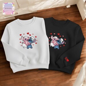 two sweatshirts with cartoon characters on them, placed on a wooden surface.