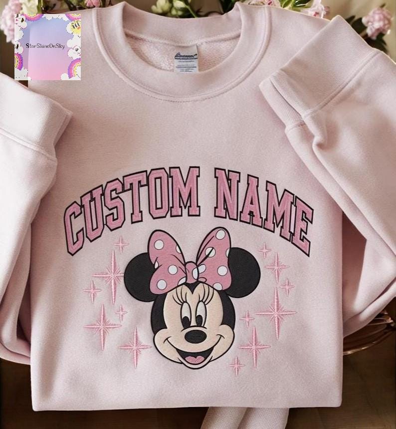 A pink sweatshirt with a Minnie Mouse design and the text "CUSTOM NAME" printed on it.