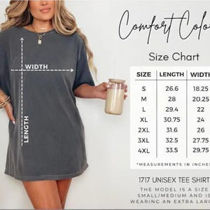 May include: Dark grey unisex tee shirt with a size chart. The chart shows measurements in inches for sizes S to 4XL. The model is wearing an extra large. The shirt is labeled "1717 UNISEX TEE SHIRT" and the brand is "Comfort Colors".