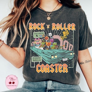 May include: Dark gray t-shirt featuring a graphic of the Muppets in a car with the text "ROCK 'N ROLLER COASTER". The design includes road signs and the phrase "DETOUR AHEAD GET READY TO ROLL!!!".