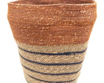 Cesta de hierba marina india tejida a mano en terracota, con detalles en color natural e índigo.