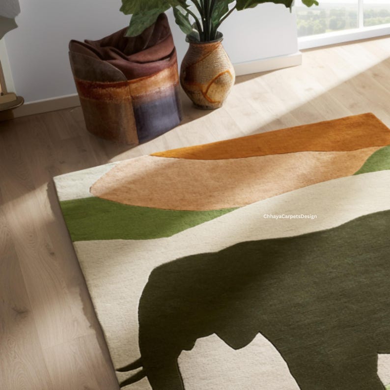 May include: A rectangular area rug with an abstract design featuring green, tan, and orange shapes. A large black elephant silhouette is visible on the rug. The rug is on a light wood floor.