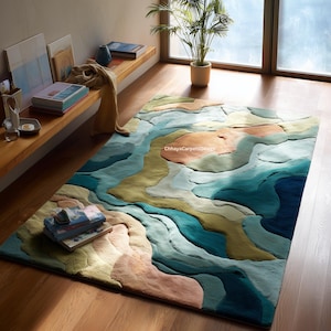 May include: A large, rectangular area rug with a layered, abstract design in shades of blue, green, and peach. The rug's textured surface creates a three-dimensional effect, resembling a landscape or water feature. The rug is placed on a wooden floor.