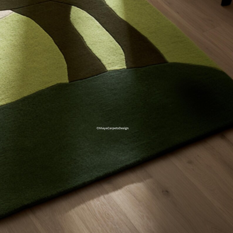 May include: A close-up of a green and brown area rug with an abstract design. The rug features a dark green base with lighter green and brown curved shapes. The text "ChhayaCarpetsDesign" is visible.
