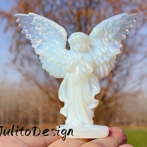 Puede incluir: Figura de ángel blanco translúcido con alas extendidas. El ángel está representado en posición de oración, con detalles de plumas en las alas. La base es rectangular. El texto "JulitoDesign" es visible.