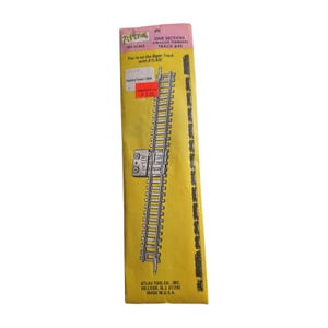 May include: An Atlas HO scale one section straight terminal track #40 in original yellow and pink packaging. The package features the text Atlas, You're on the Right Track with ATLAS!, HobbyTown USA, and Atlas Tool Co., Inc. Hillside, N.J. 07205.