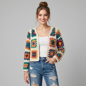Könnte beinhalten: Eine cremefarbene, offene Häkeljacke mit bunten quadratischen Mustern. Die Quadrate weisen Türkis-, Rosa-, Gelb- und Burgundertöne auf. Die Strickjacke hat lange Ärmel und eine lockere Passform.