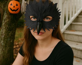 May include: A black raven mask with a beak and feather details. The mask is worn by a person. A carved orange pumpkin and a white ghost decoration are in the background, suggesting a Halloween theme.