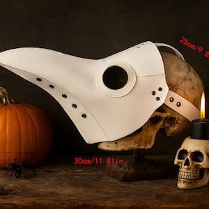 Puede incluir: Una m&aacute;scara de m&eacute;dico de la peste de cuero blanco con un pico largo, un cr&aacute;neo de 30 cm y una vela encendida. Tambi&eacute;n hay una calabaza naranja (25 cm) y un peque&ntilde;o candelabro de calavera, junto con una ara&ntilde;a de pl&aacute;stico.