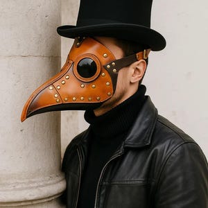 May include: A brown leather plague doctor mask with a long beak, riveted details, and large eye openings. The mask is worn with a black top hat, a black turtleneck, and a black leather jacket. The mask is a unique costume piece.