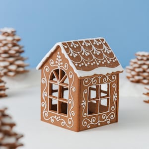May include: A brown gingerbread house with white icing decorations on the roof and walls. The structure features arched and rectangular window cutouts with intricate piped scrollwork patterns. The roof is topped with a thick layer of white icing.