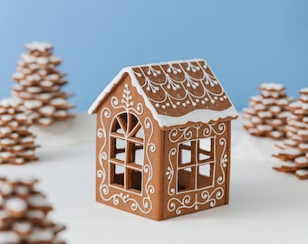 May include: A brown gingerbread house with white icing decorations on the roof and walls. The structure features arched and rectangular window cutouts with intricate piped scrollwork patterns. The roof is topped with a thick layer of white icing.